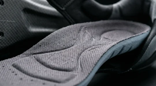 Close-up view of custom arch support cycling insole inside performance shoe highlighting metatarsal support and anatomical contours