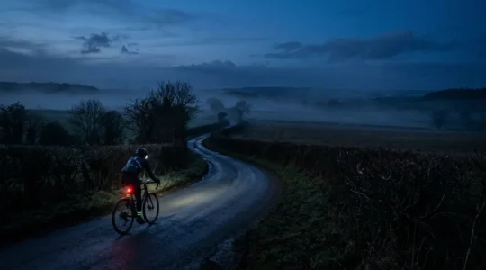 Cyclist riding on unlit rural country lane at dusk with strategic visibility lighting