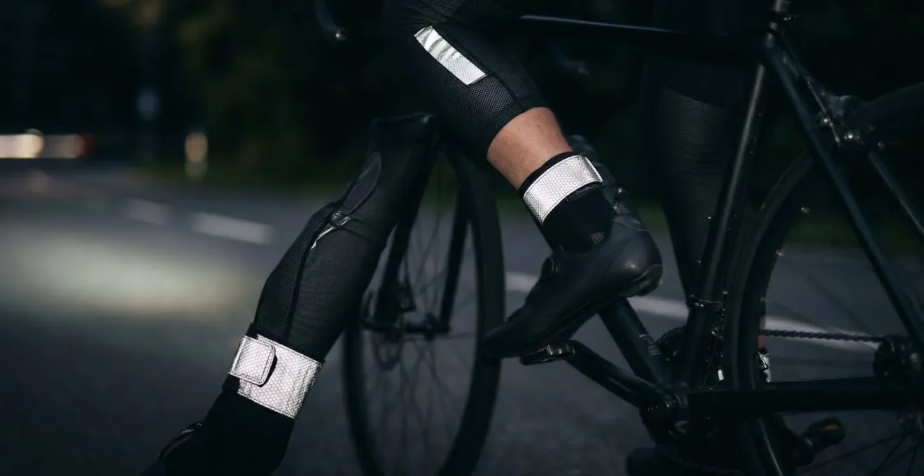 Close-up of cyclist's legs in motion showing reflective strips on ankles and knees creating biological movement pattern