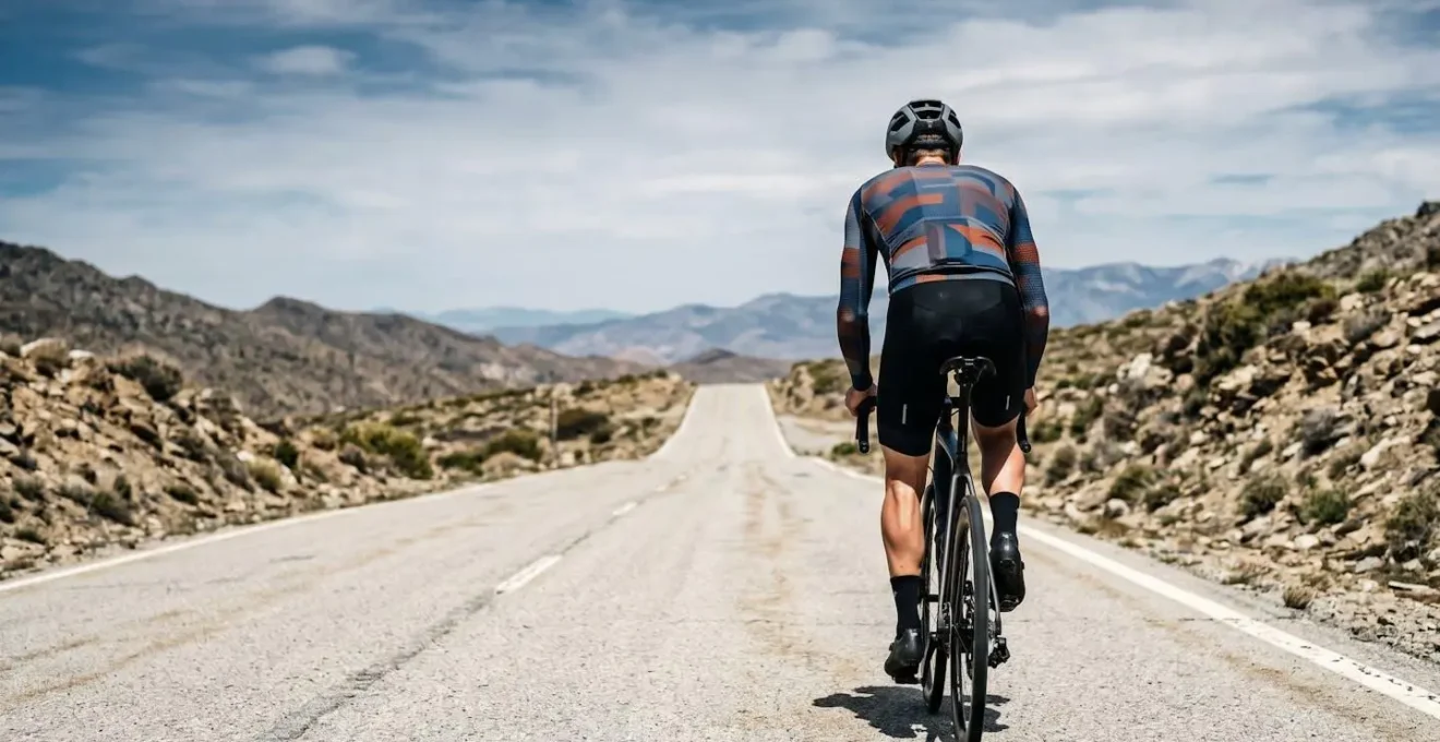 Endurance cyclist on mountain road showing physical exertion and heat stress during long ride