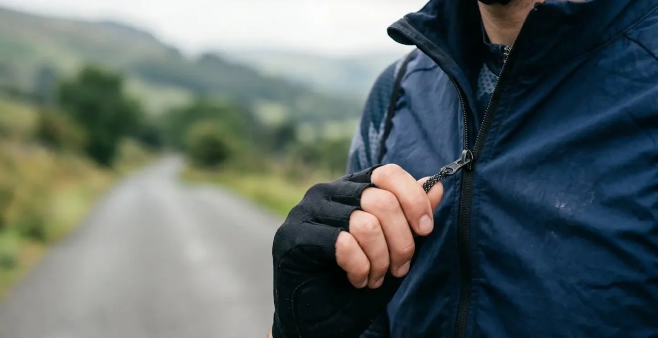 Close-up of a cyclist adjusting the two-way zipper on their gilet during a climb for ventilation control
